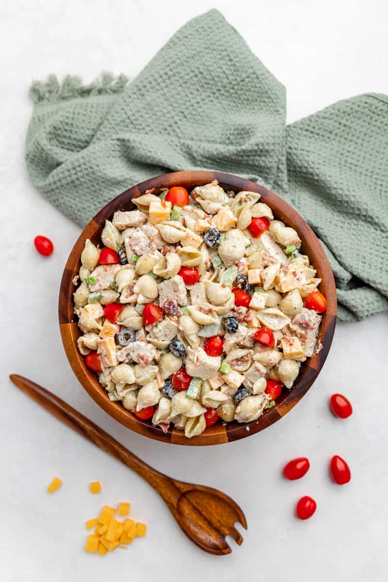 An overhead view of chicken bacon ranch pasta salad in a wooden serving bowl.