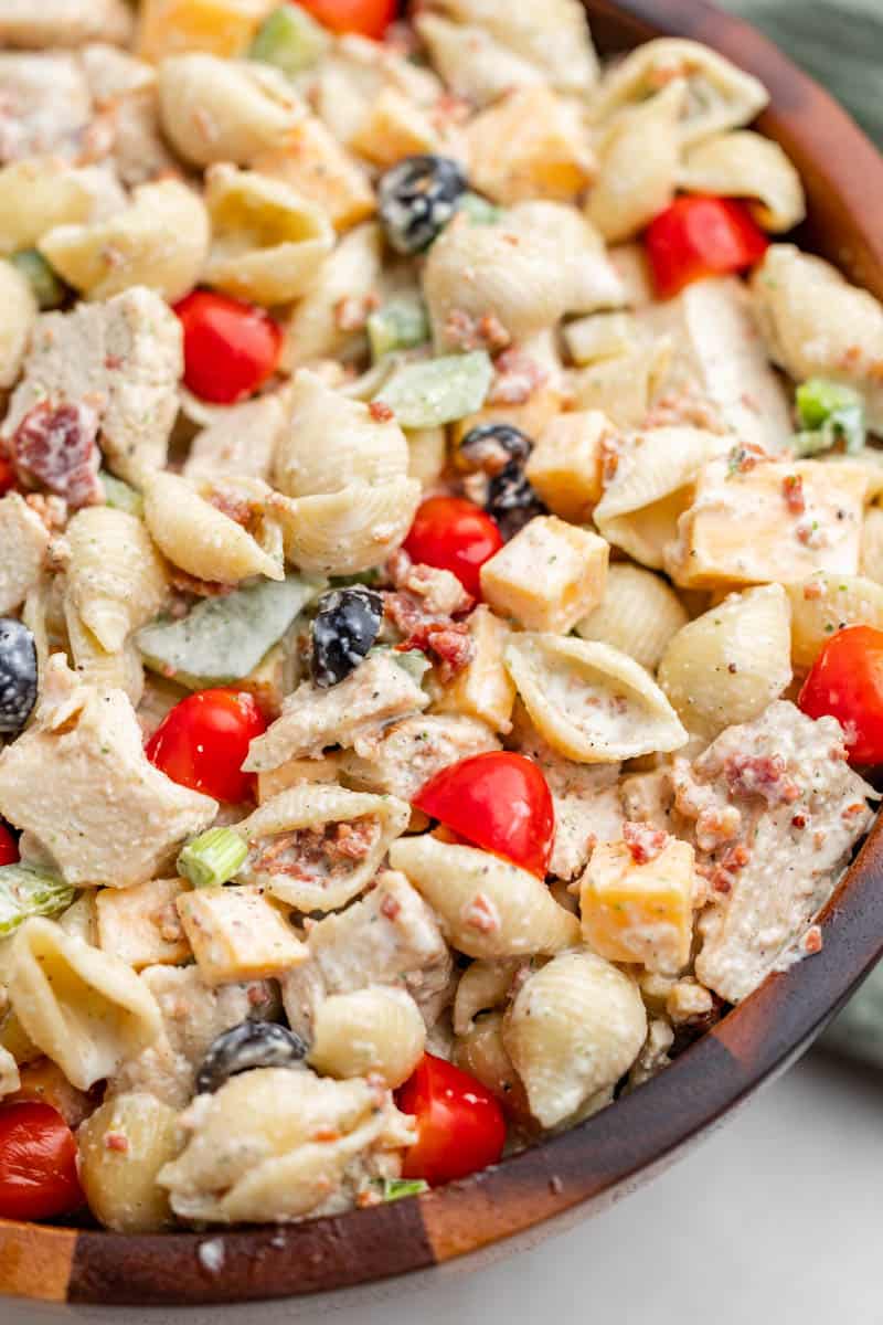 Close-up of chicken bacon pasta salad in a wooden serving bowl.