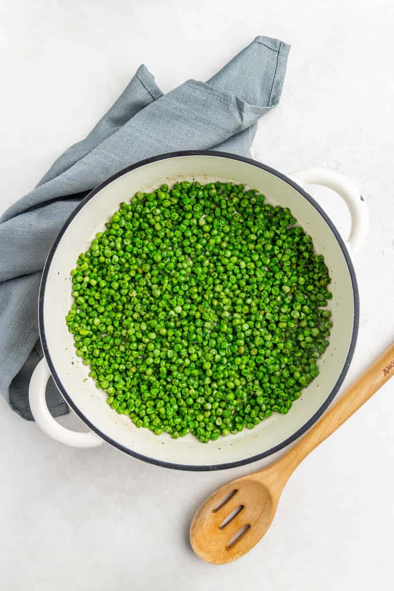 Overhead view of cooked peas in a white pot.
