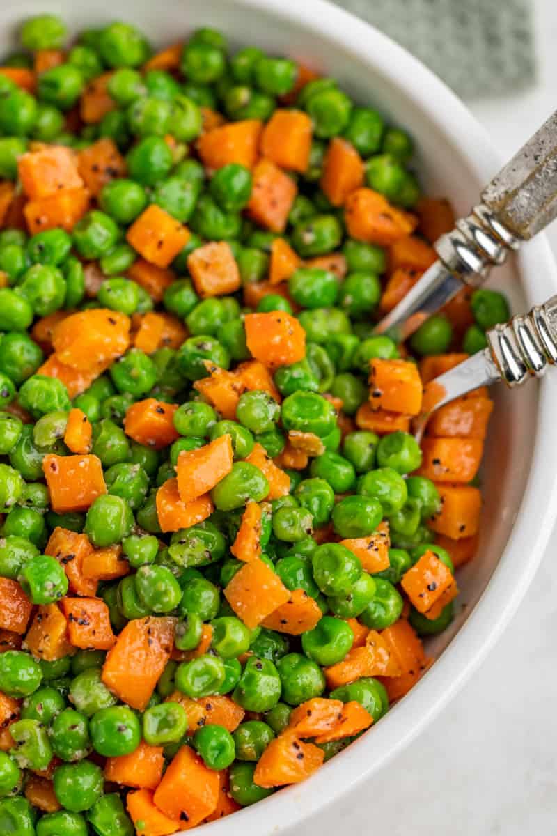 Overhead view of peas and carrots in a bowl.;