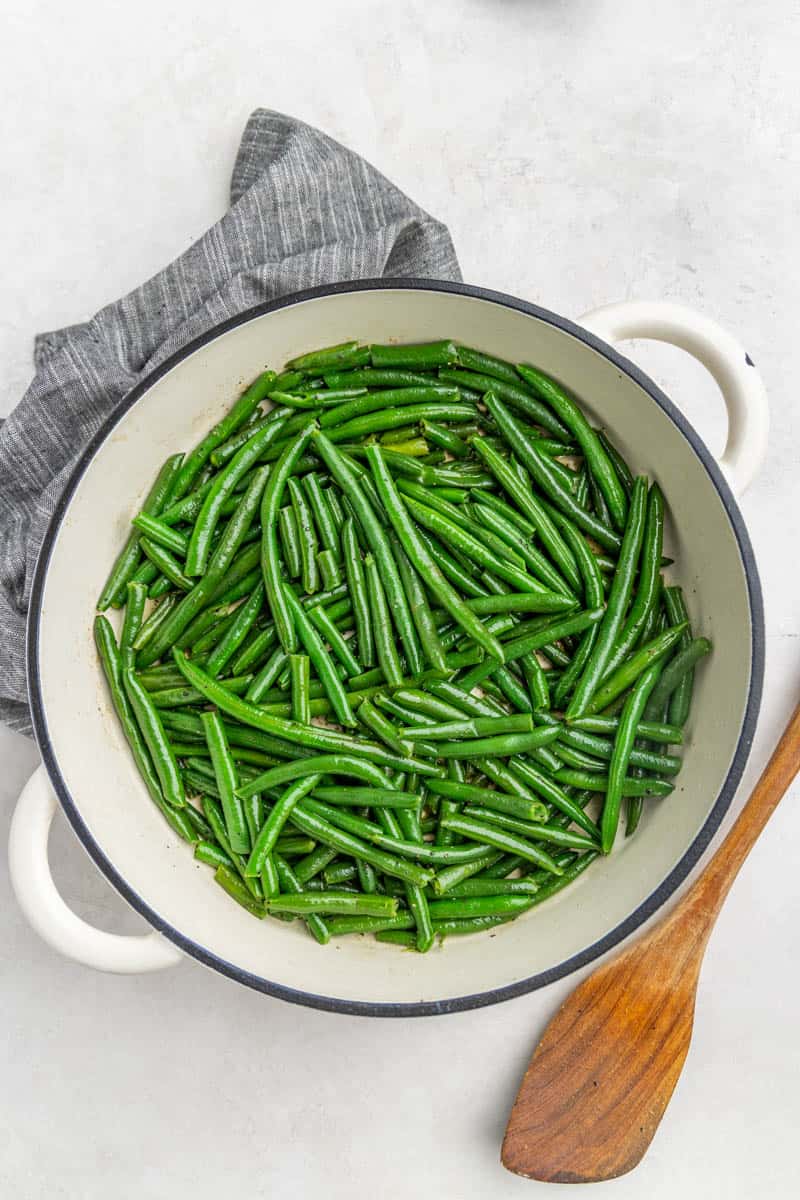 Top view of green beans cooked frozen in a white pan.