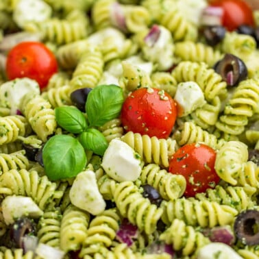 Close up view inside a bowl filled with pesto pasta salad.