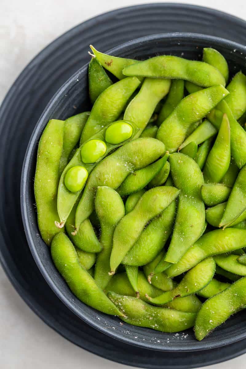 Overhead view of edamame in a black bowl.