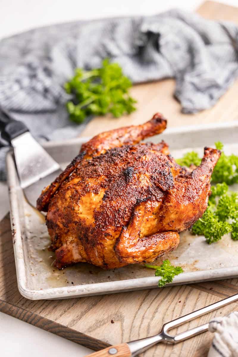 A whole smoked chicken on a baking sheet.