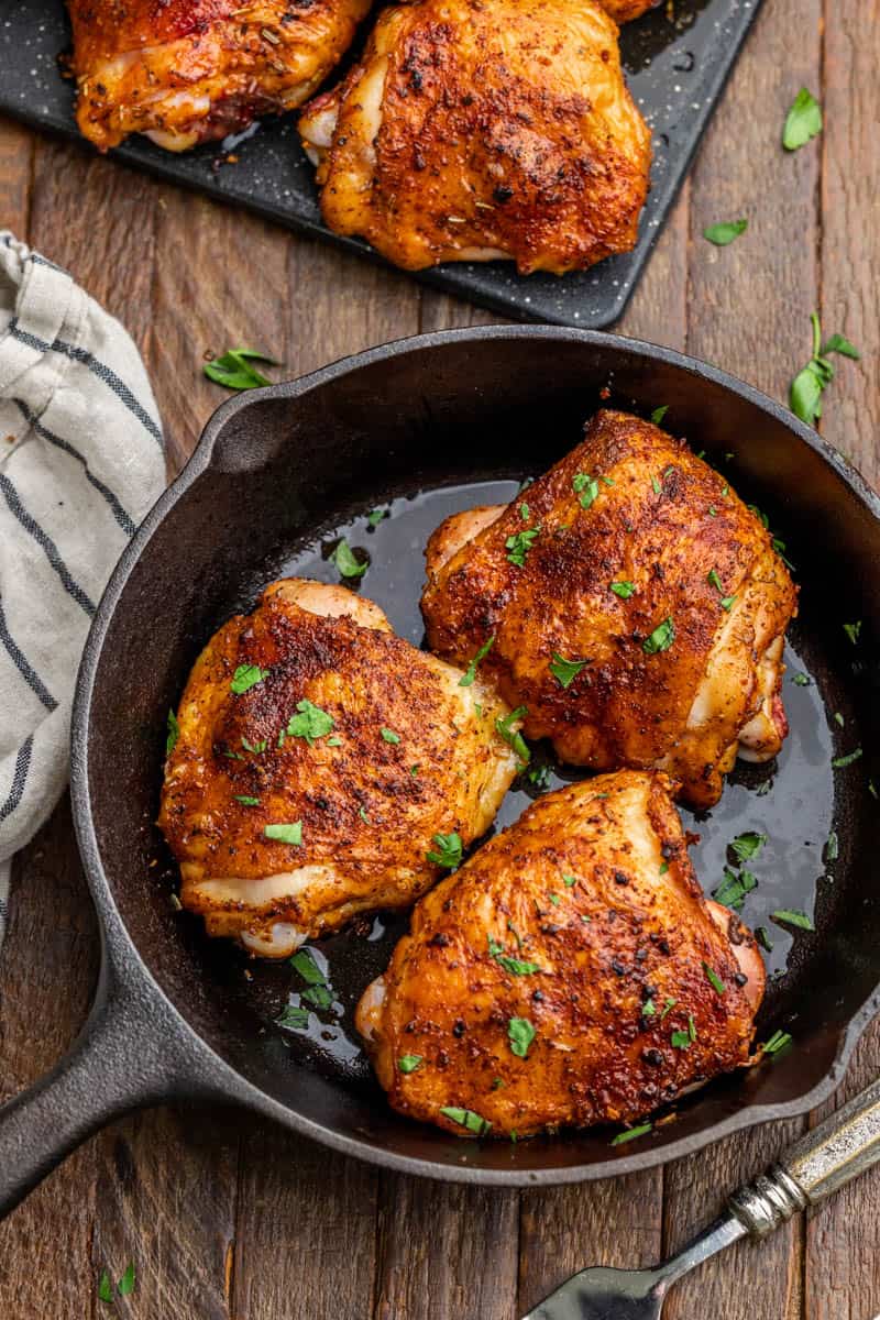 Overhead view of smoked chicken thighs in a cast iron pan.