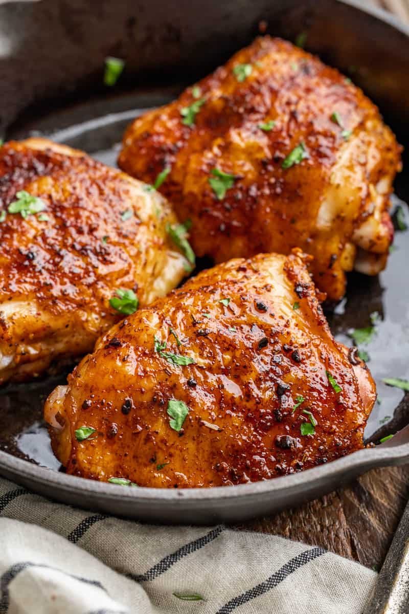 Close up view of smoked chicken thighs in a cast iron pan.