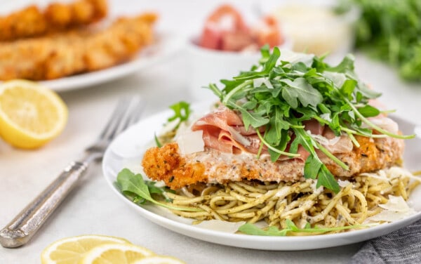 A plate with spaghetti, better than Bellagio chicken, and arugula on top.