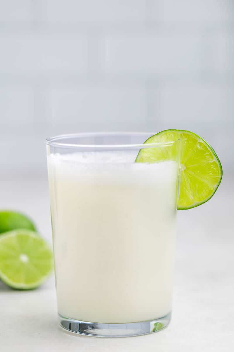 A glass of Brazilian lemonade with a lime slice on the rim.