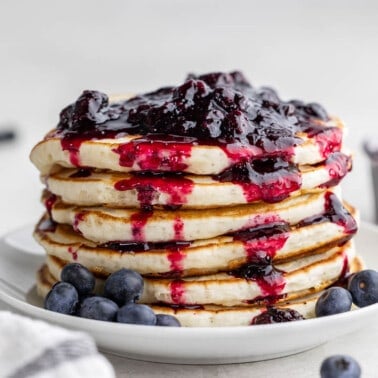 A stack of pancakes with homemade blueberry syrup on top.