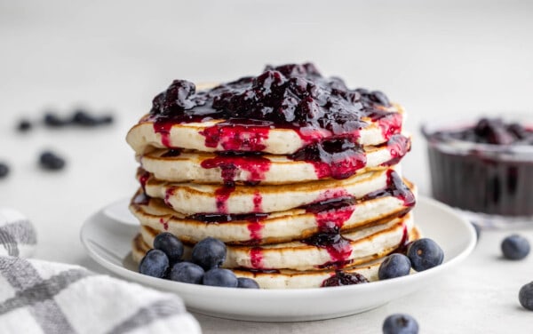 A stack of pancakes with homemade blueberry syrup on top.
