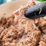 BBQ pulled pork held in tongs.