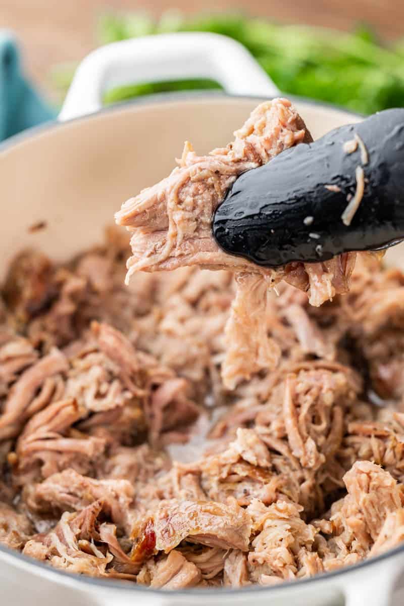 BBQ pulled pork held in tongs.