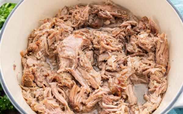 Overhead view looking into a dutch oven filled with BBQ pulled pork.