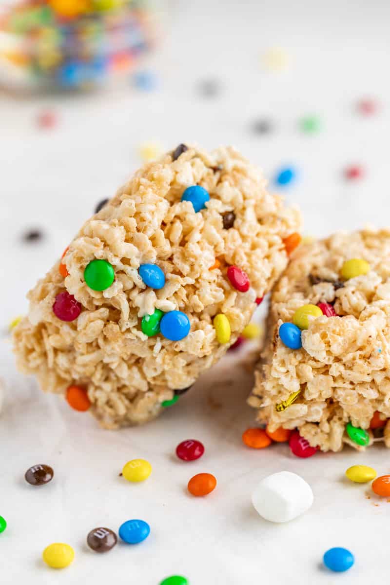 Two Rice Krispie treats with m&ms on a kitchen counter.