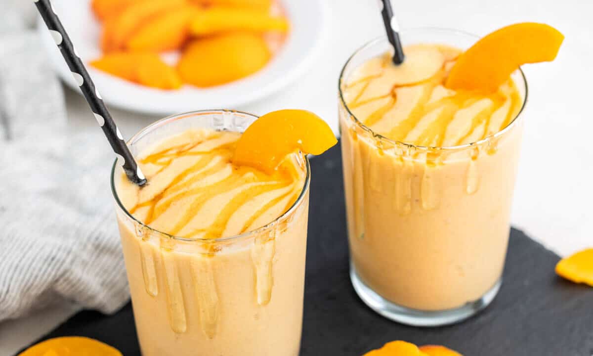 Close up view of two glasses filled with peach smoothies.