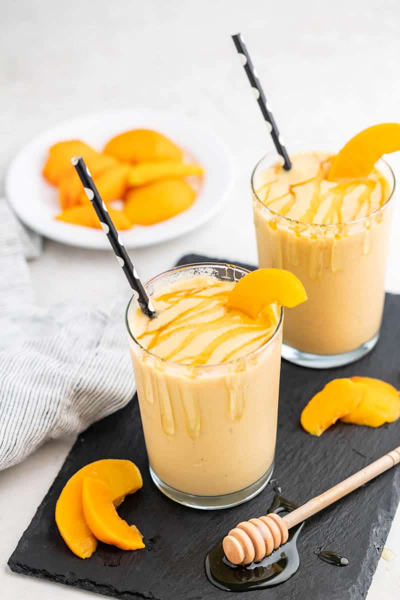 Two glasses with peach smoothie inside.