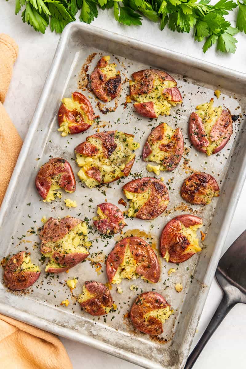 Overhead view of garlic herb smashed potatoes on a baking sheet.