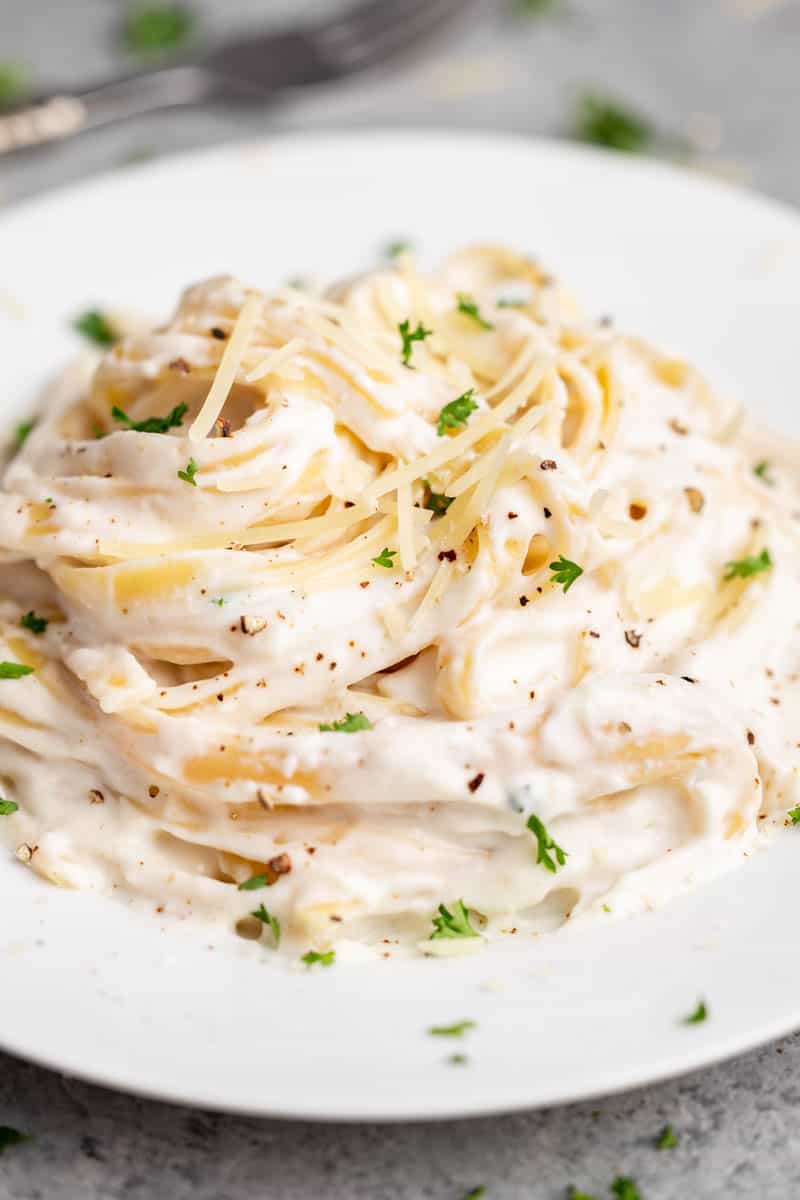 Close up view of fettuccine Alfredo on a white plate.