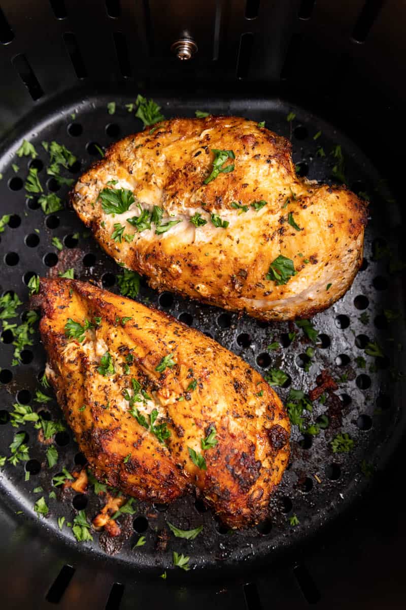 Chicken breasts cooked from frozen in an air fryer basket.