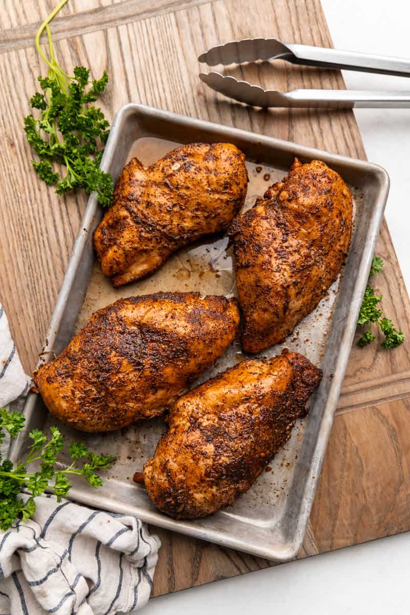 Overhead view of smoked chicken breasts on a cooking sheet.