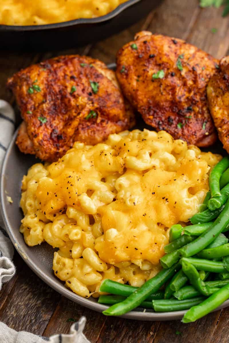 Overhead view of smoked mac and cheese on a dinner plate with chicken thighs.