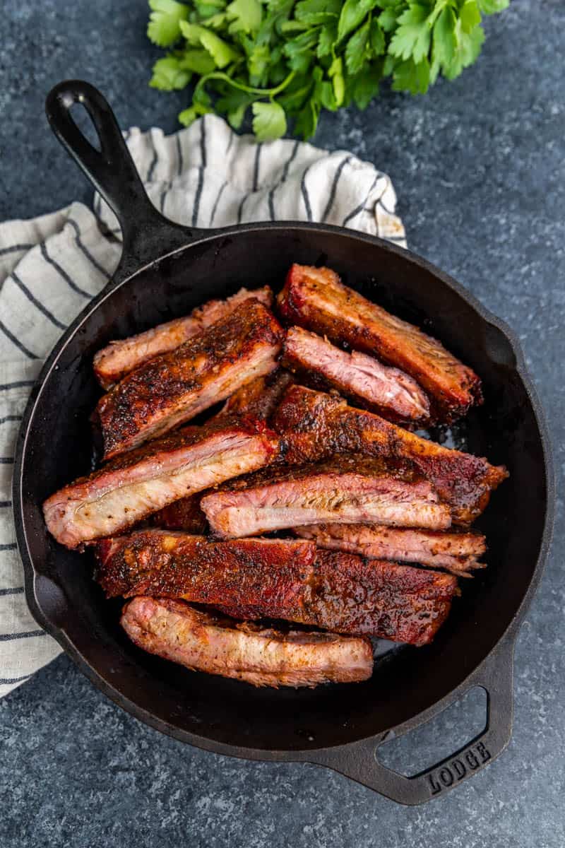 Overhead view of smoked ribs in a cast iron pan.