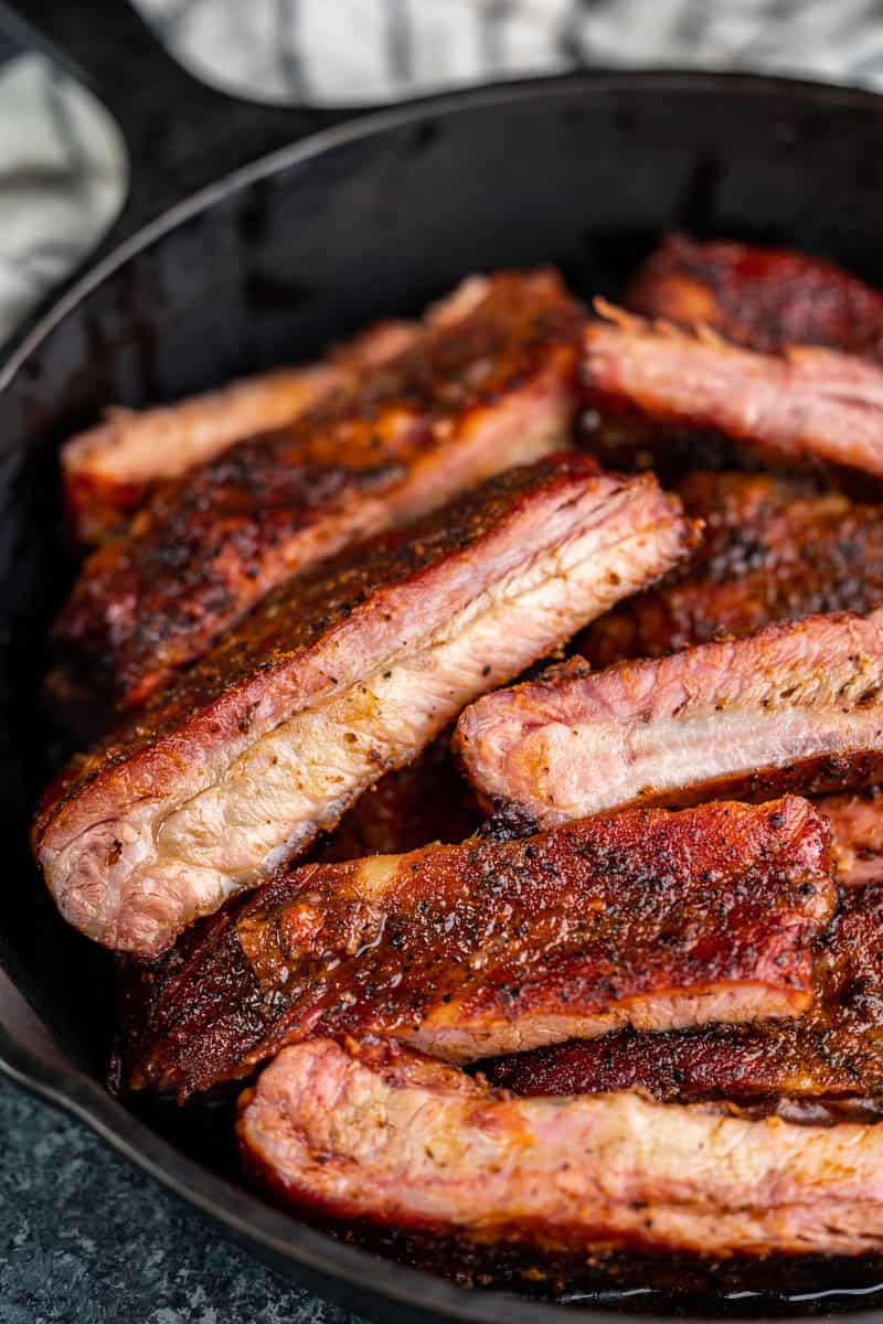 Close up view of smoked ribs in a cast iron skillet.