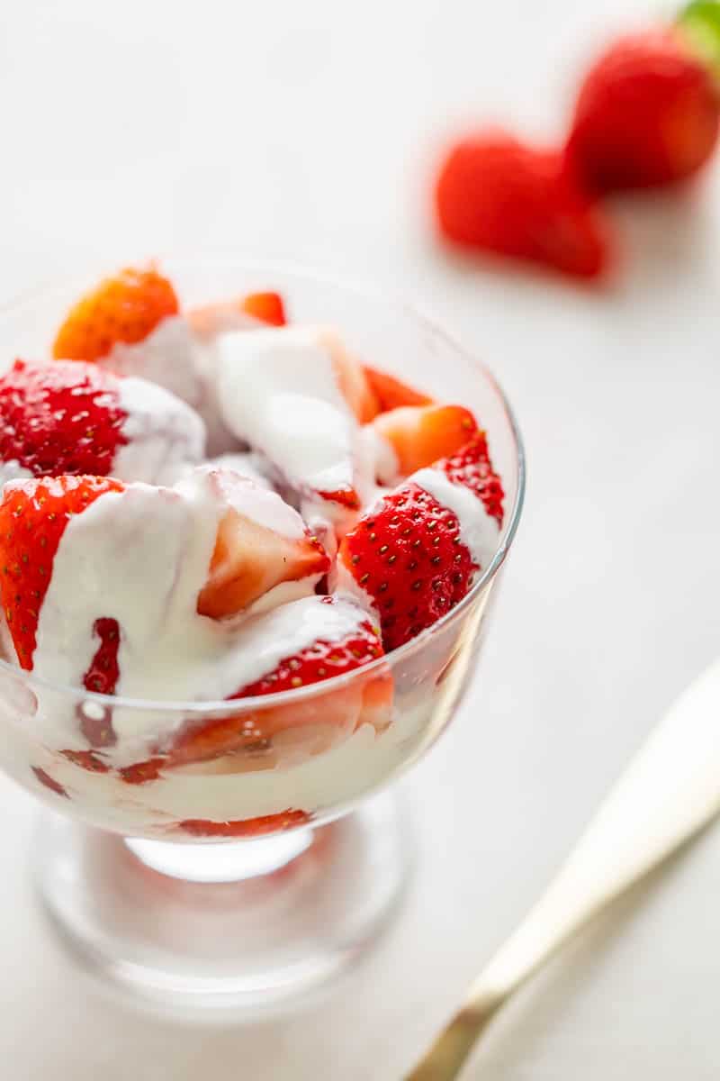 Strawberries and cream in a small glass dish.