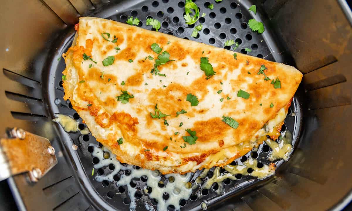 Overhead view of a quesadilla in an air fryer basket.