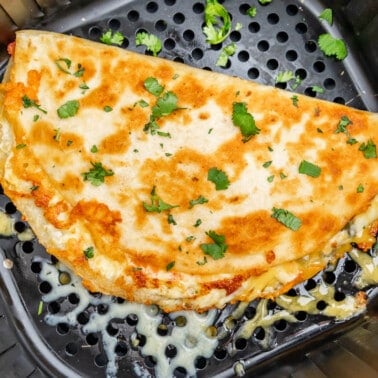 Overhead view of a quesadilla in an air fryer basket.