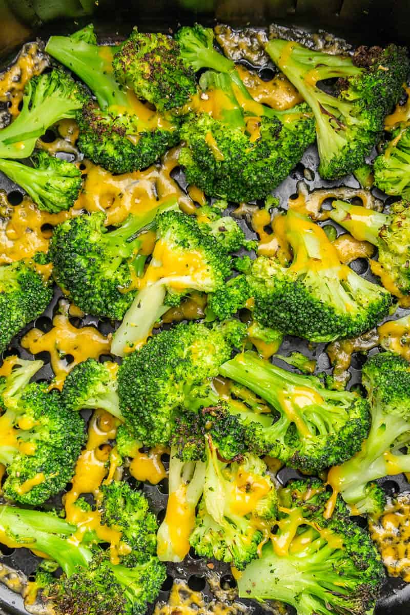 Cheesy broccoli in an air fryer basket.