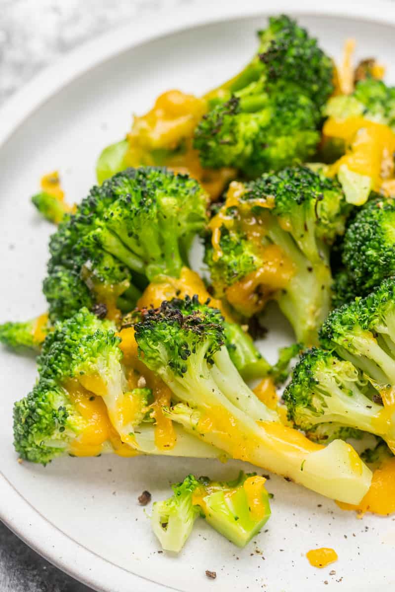 Overhead view of cheesy air fryer broccoli on a dinner plate.