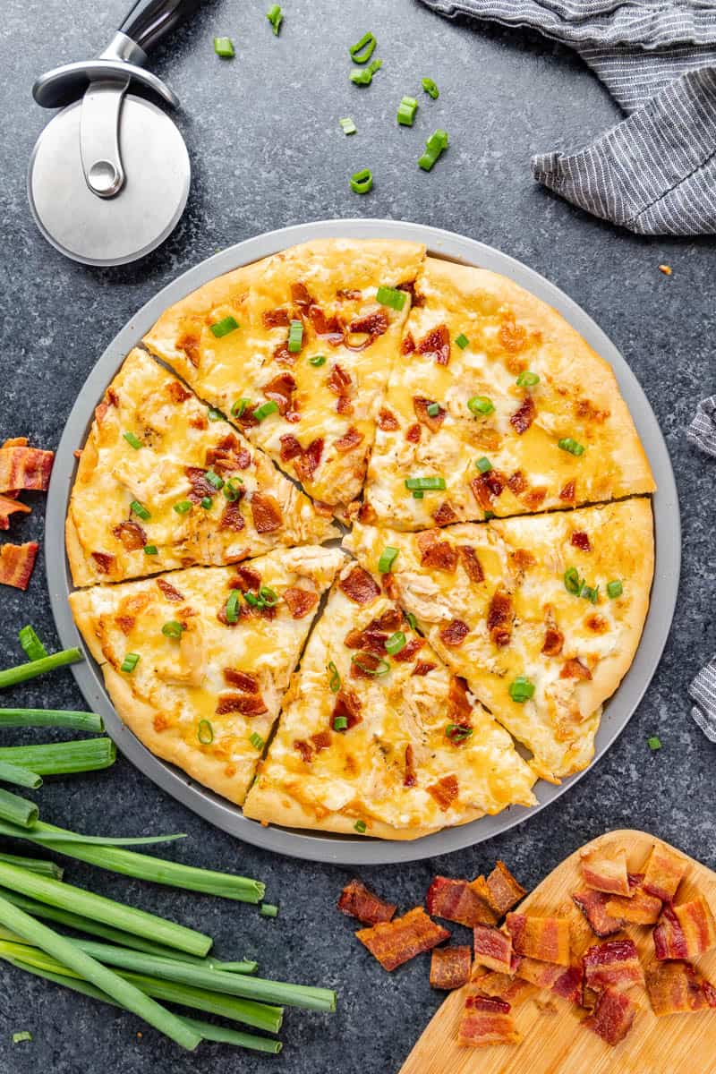 Overhead view of a chicken bacon ranch pizza cut into slices.