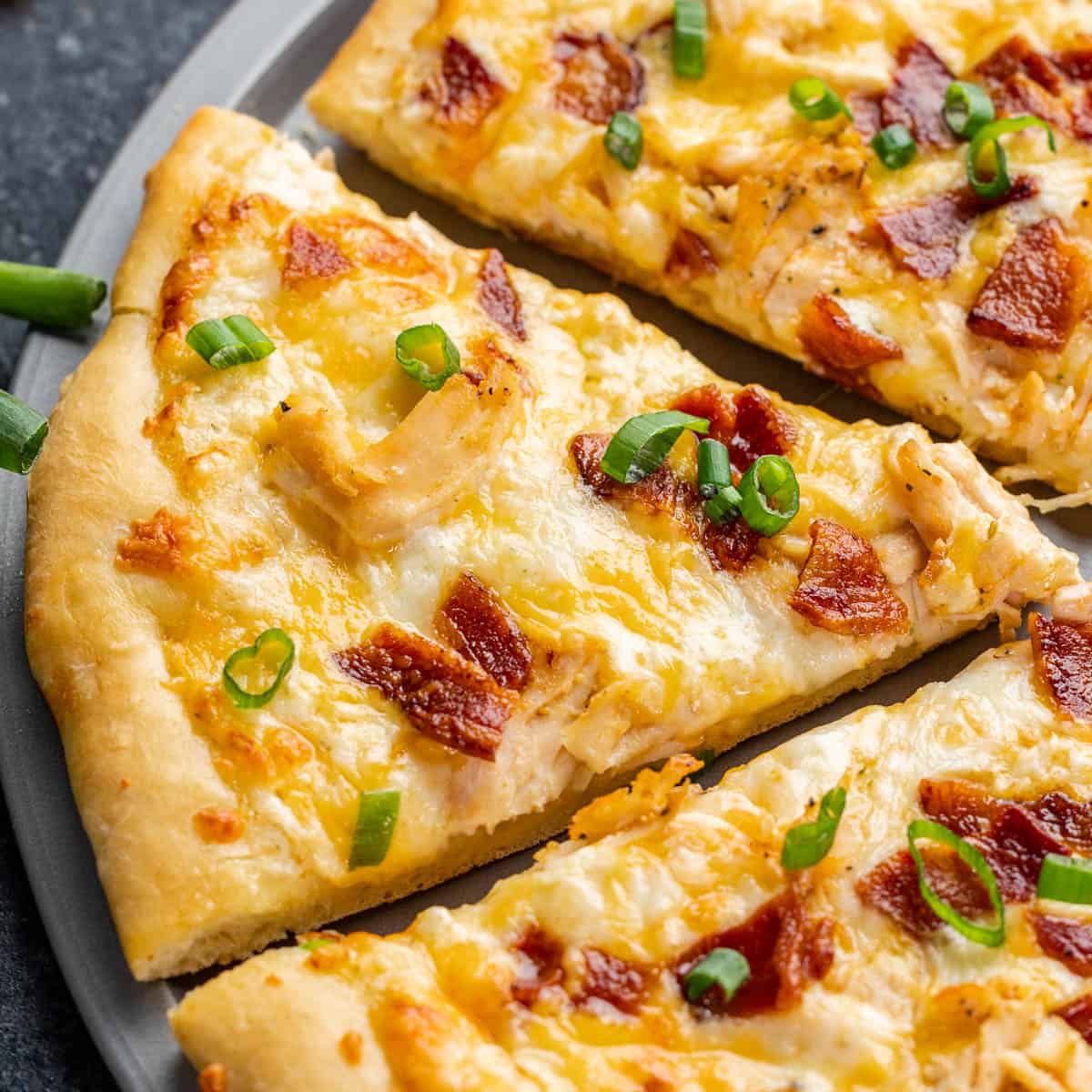 An overhead view of a chicken bacon ranch pizza cut into slices.