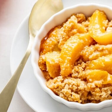 Overhead view of peach crumble in a small serving dish.