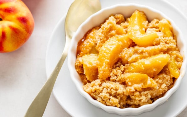 Overhead view of peach crumble in a small serving dish.