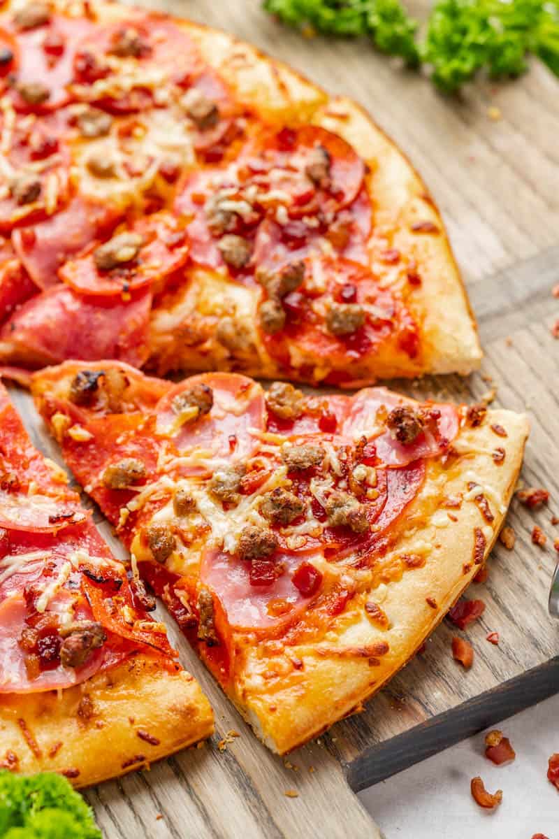 Meat lovers pizza on a wood tray.