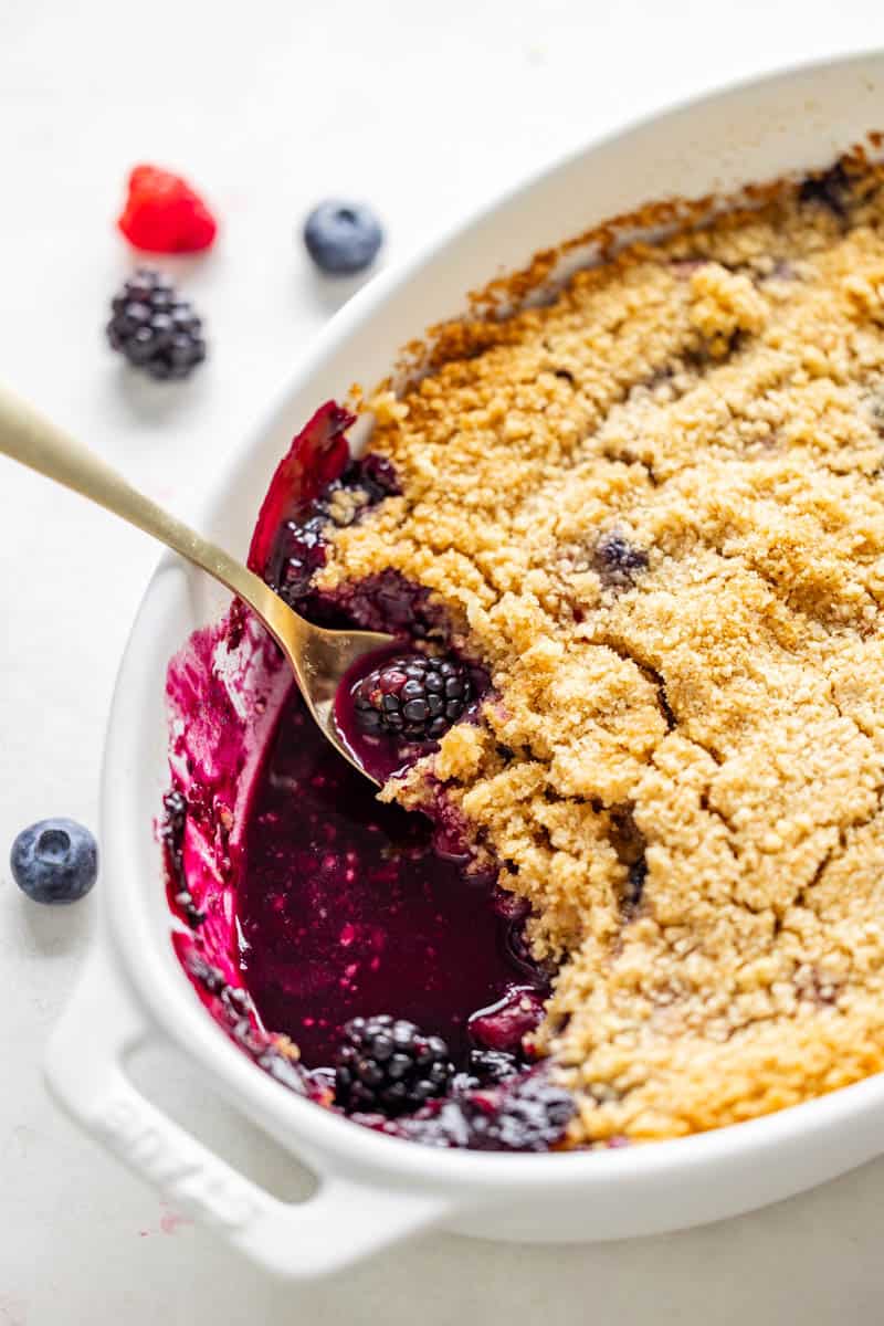 Overhead view of a mixed berry crumble in a white baking dish.