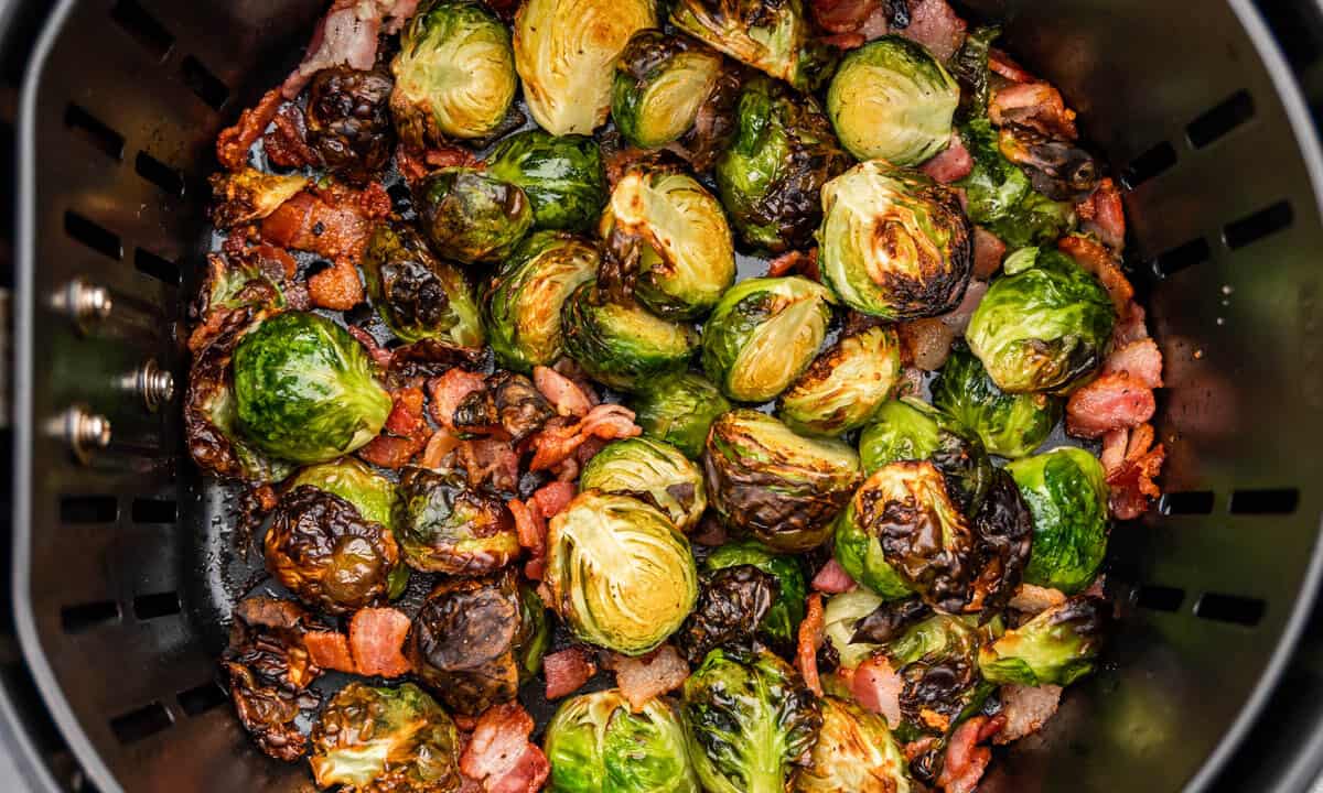 Overhead view looking into an air fryer basket with brussel sprouts and bacon.
