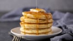 A stack of pancakes with syrup being drizzled over the top.