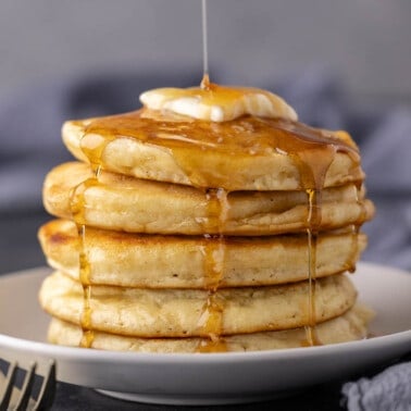 A stack of pancakes with syrup being drizzled over the top.