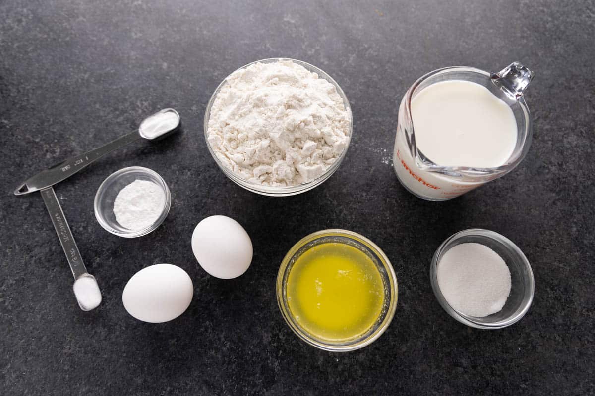 The raw ingredients needed to make pancakes on a clean counter.