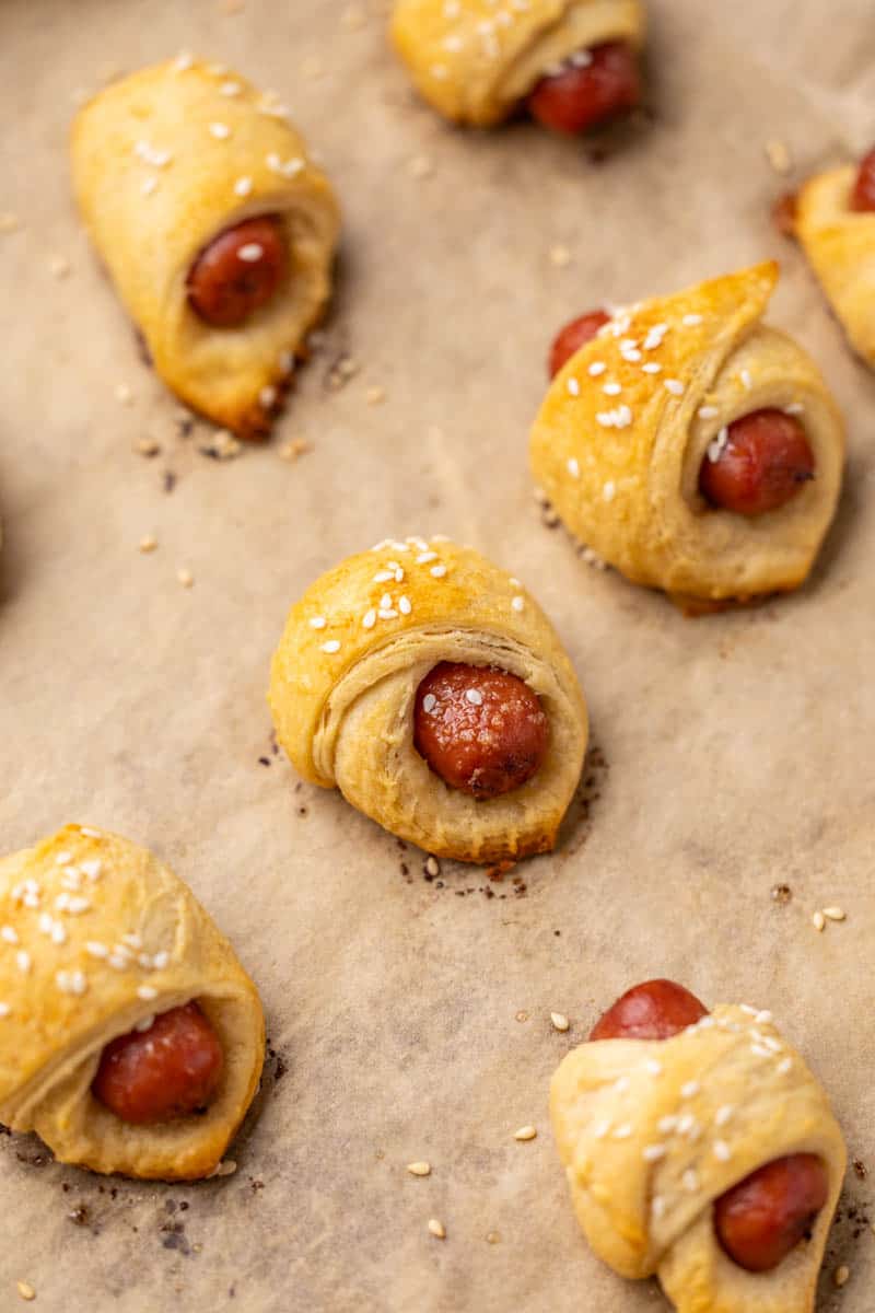 Pigs in a blanket on a parchment lined baking sheet.