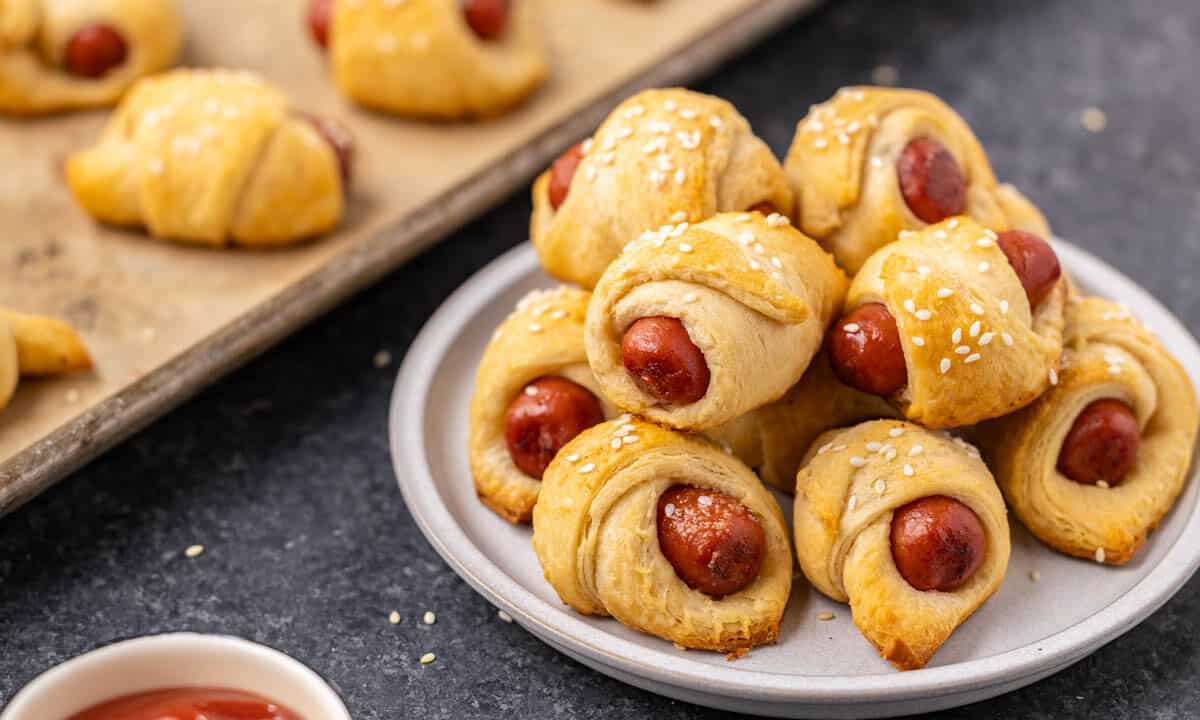 Pigs in a blanket stacked on a dinner plate.