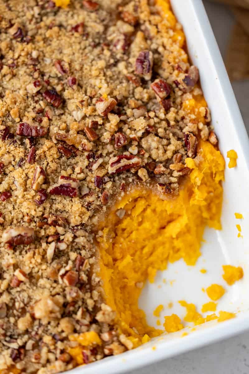 Overhead view of a baking dish filled with sweet potato casserole, with a serving removed.