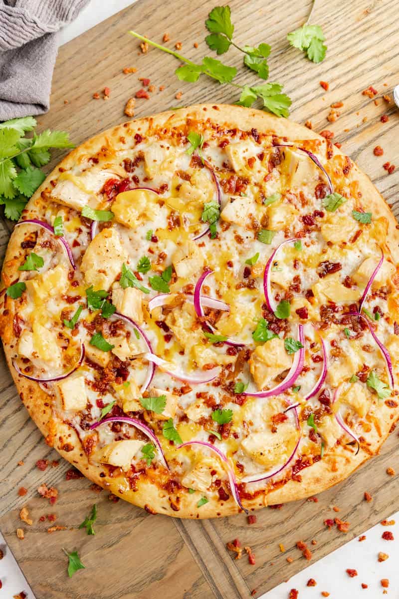 An overhead view of a whole, uncut bbq chicken pizza.