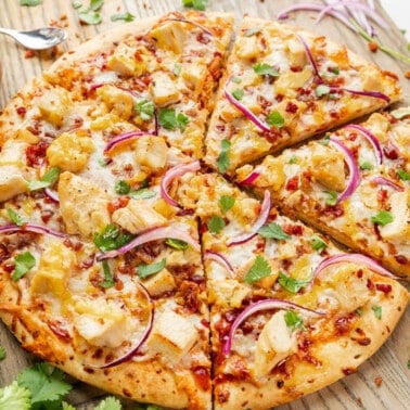 Overhead view of a bbq chicken pizza on a wood serving platter.