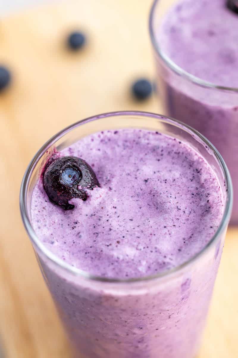 Close up overhead view of a homemade blueberry smoothie in a tall glass.