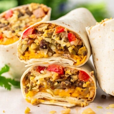 Breakfast burrito halves that have been stacked on top of each other on a kitchen counter.