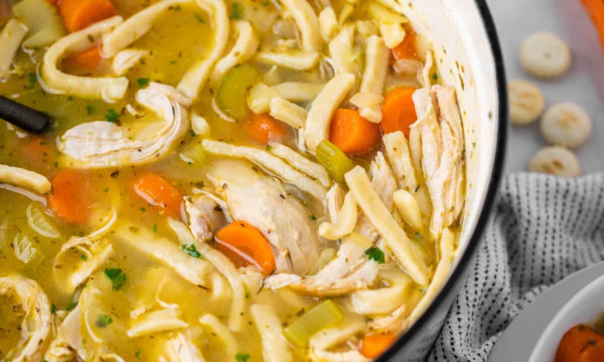 Close up overhead view of chicken noodle soup in a large pot.